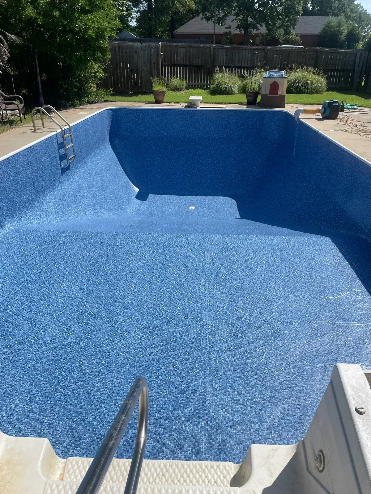 Swimming pool with blue mosaic tile interior, curved spa feature, and white coping