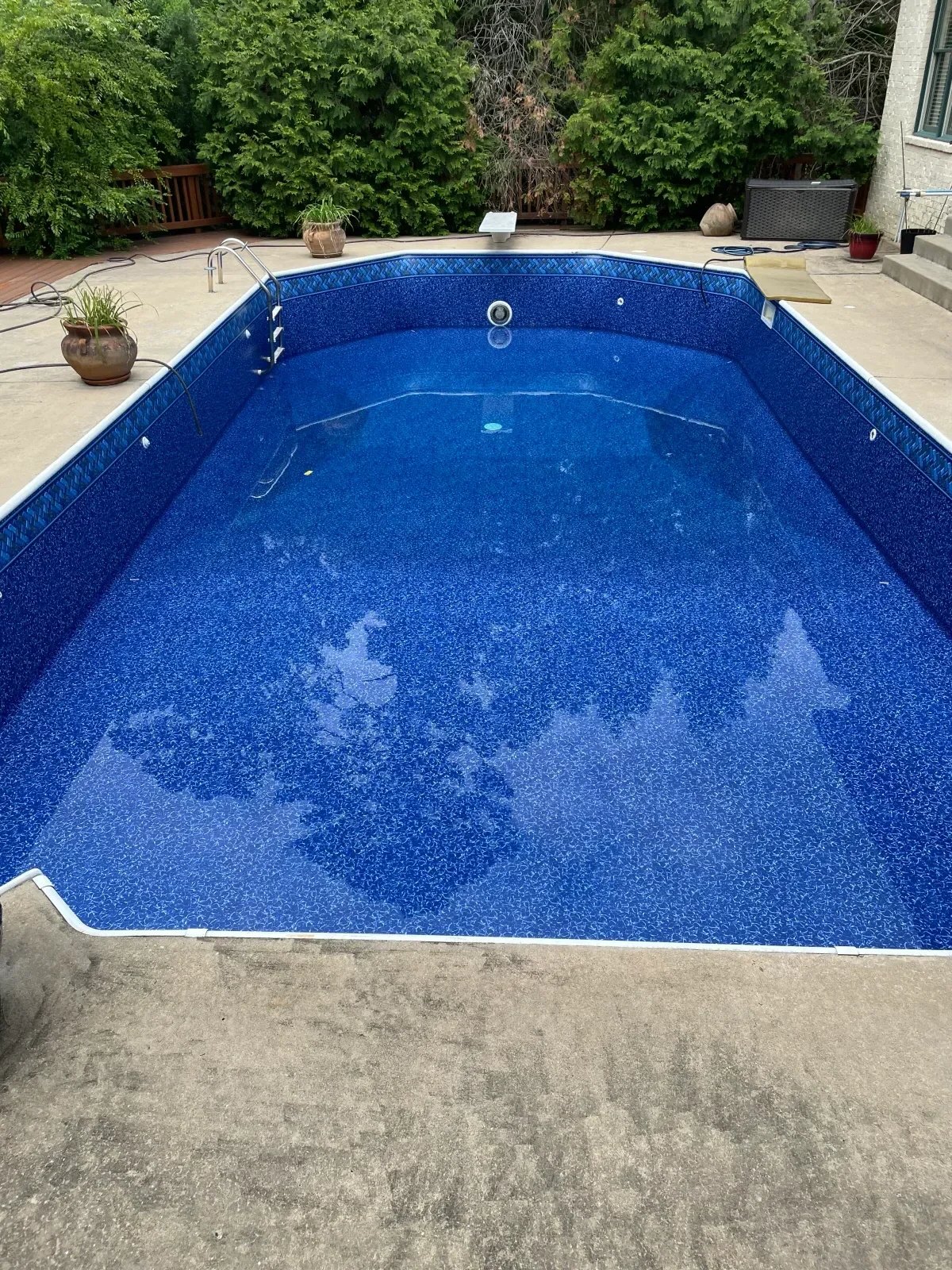 New blue textured pool liner installed in in-ground swimming pool with concrete deck
