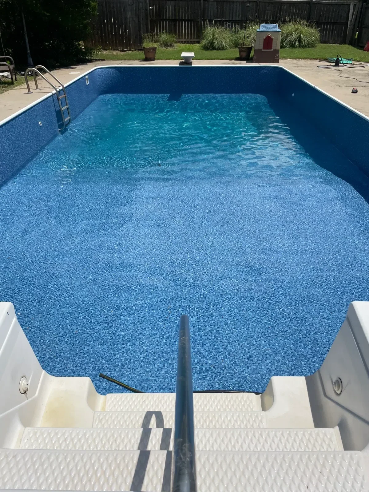 Blue mosaic tile swimming pool with curved walls and white deck surround