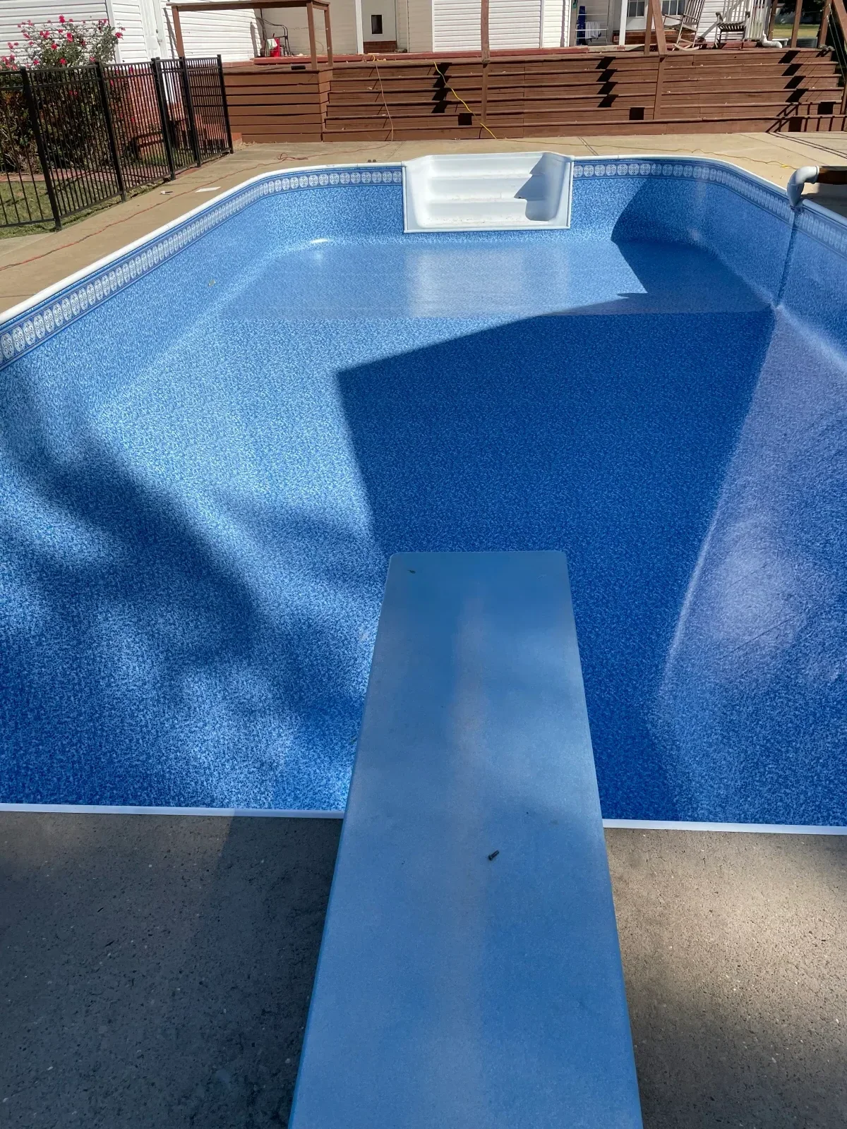 Fiberglass pool with blue interior finish, bench seating, and concrete deck installation