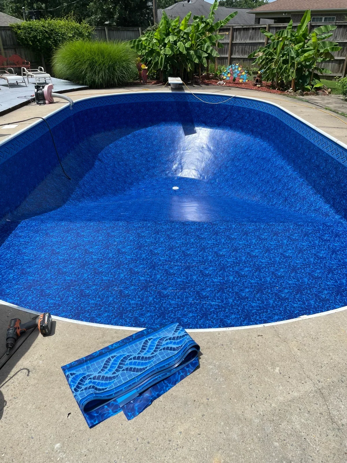Above-ground pool with new blue vinyl liner during installation, white pool wall visible