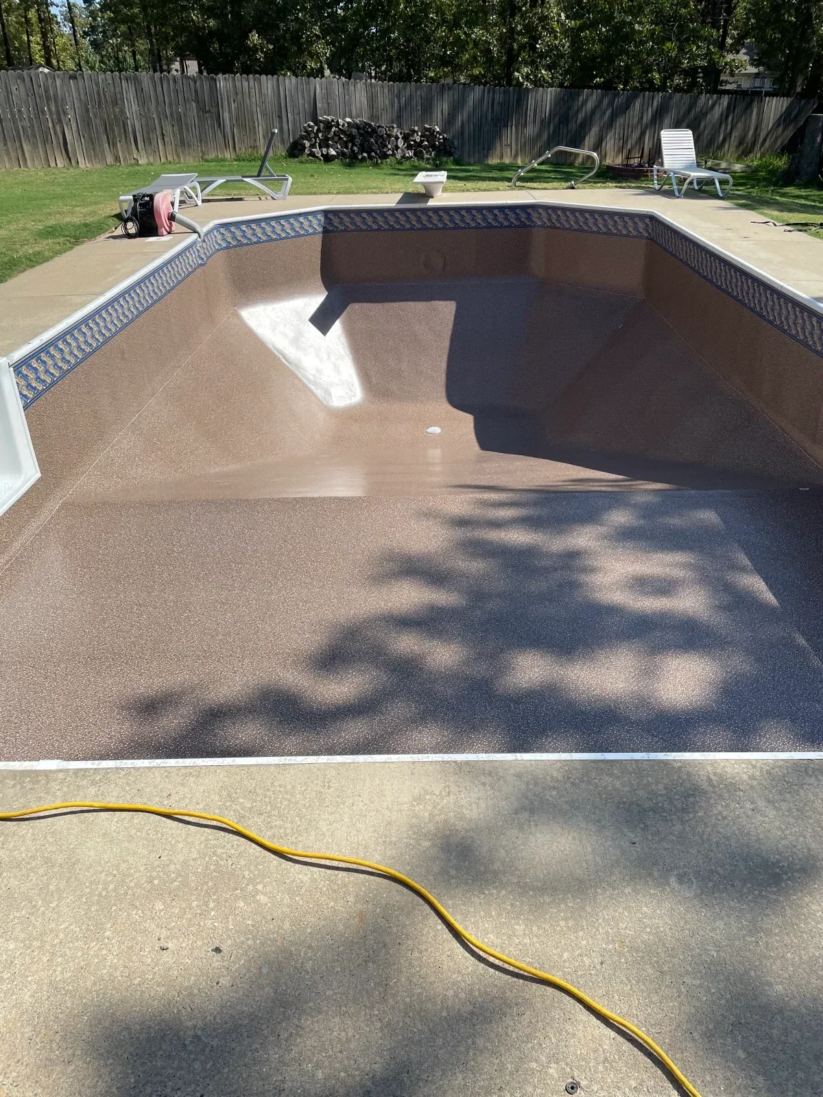 Concrete pool deck restoration with cleaned surface and yellow utility line marking