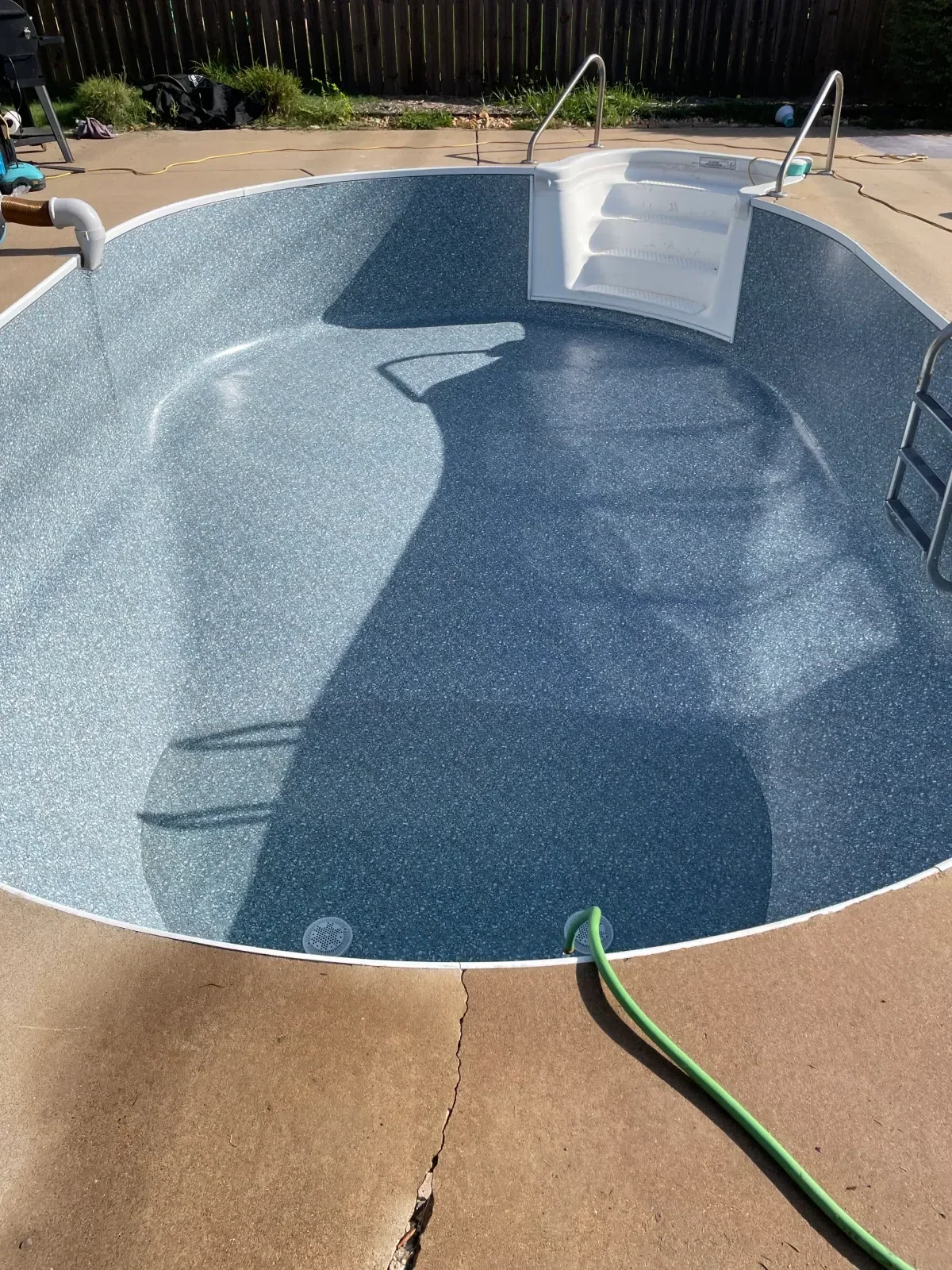 Newly resurfaced in-ground pool with slate blue aggregate finish and white coping
