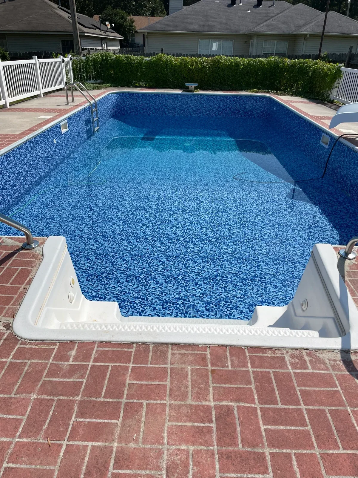 Residential swimming pool with blue pebble interior finish and white coping