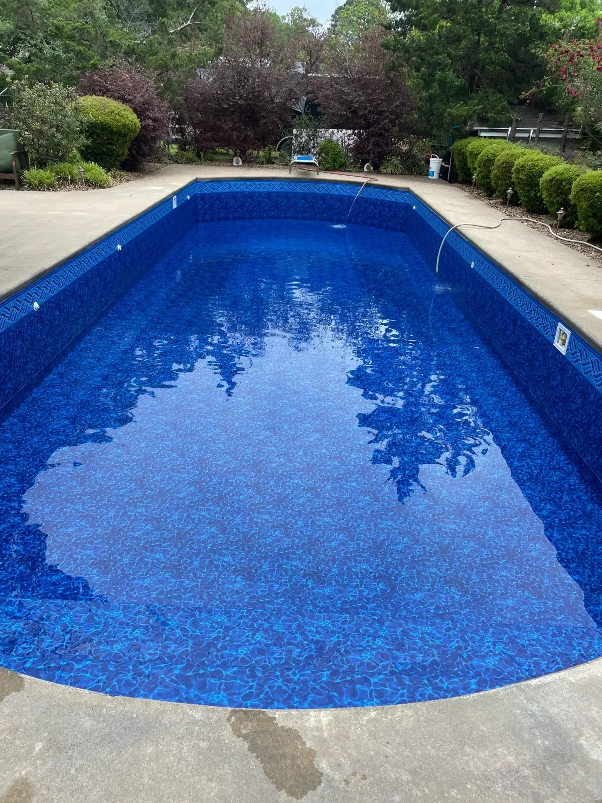In-ground pool with new blue vinyl liner and concrete deck surround
