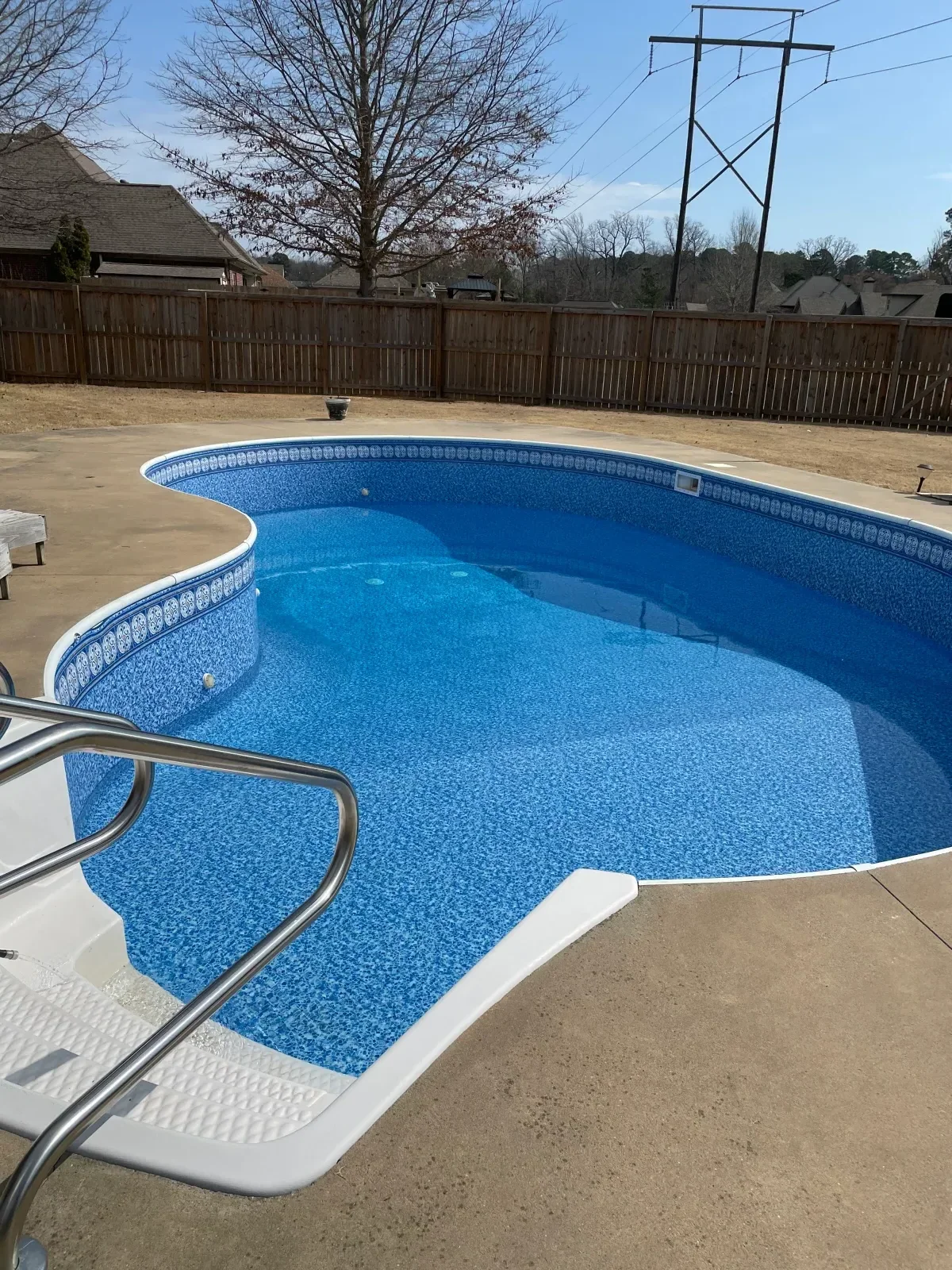 In-ground pool with blue plaster finish, white coping, and stainless steel ladder