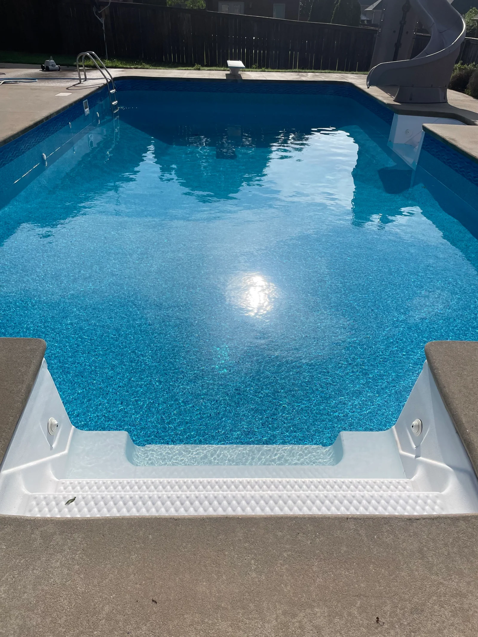 Restored in-ground pool with turquoise aggregate finish, white fiberglass steps, and clear water