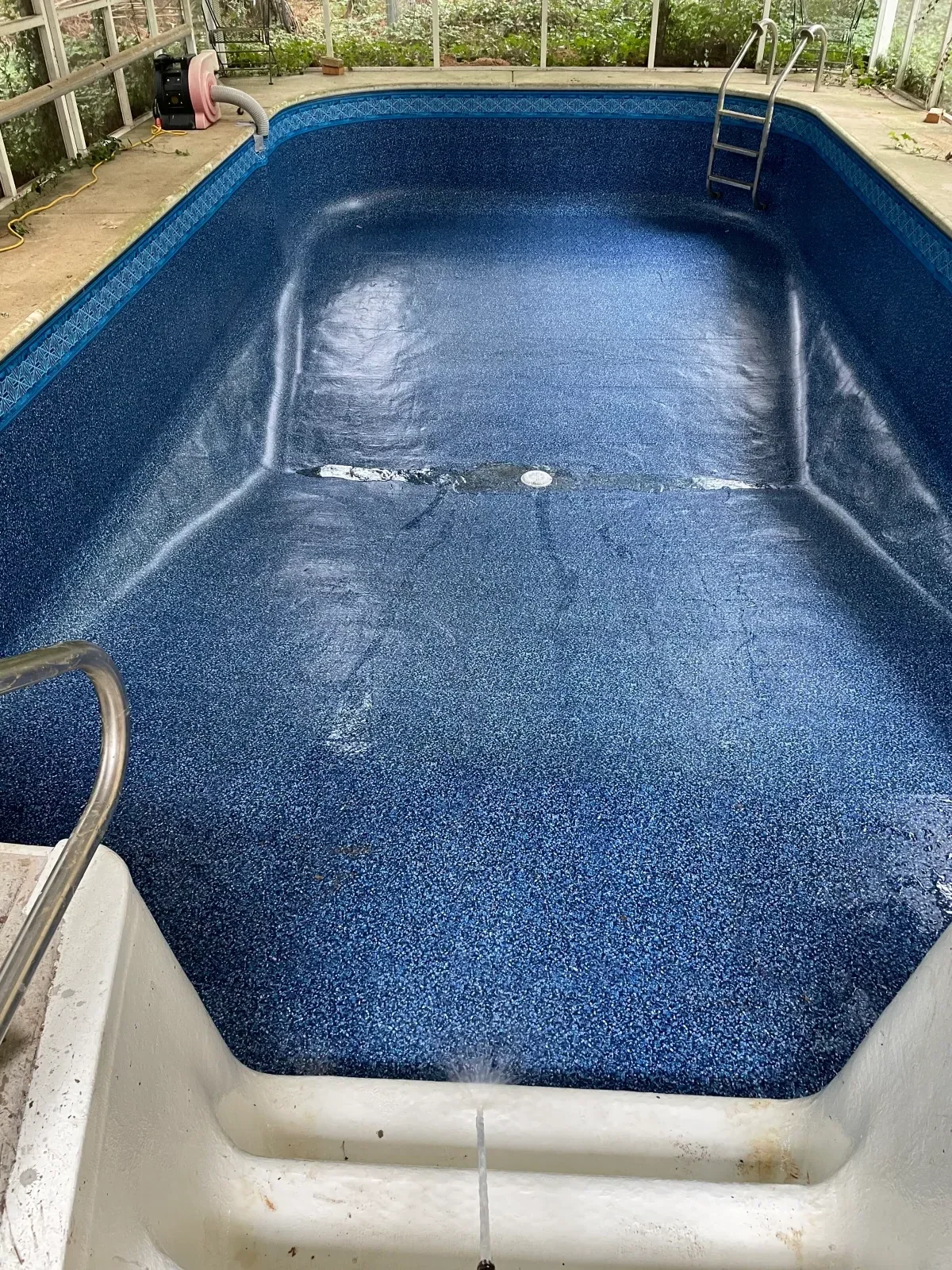 In-ground pool with dark blue aggregate interior finish and concrete deck surround