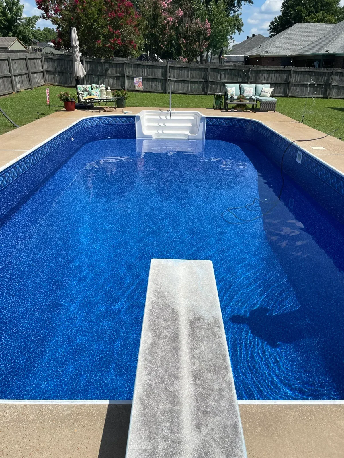 In-ground pool with new blue vinyl liner, concrete decking, and white coping