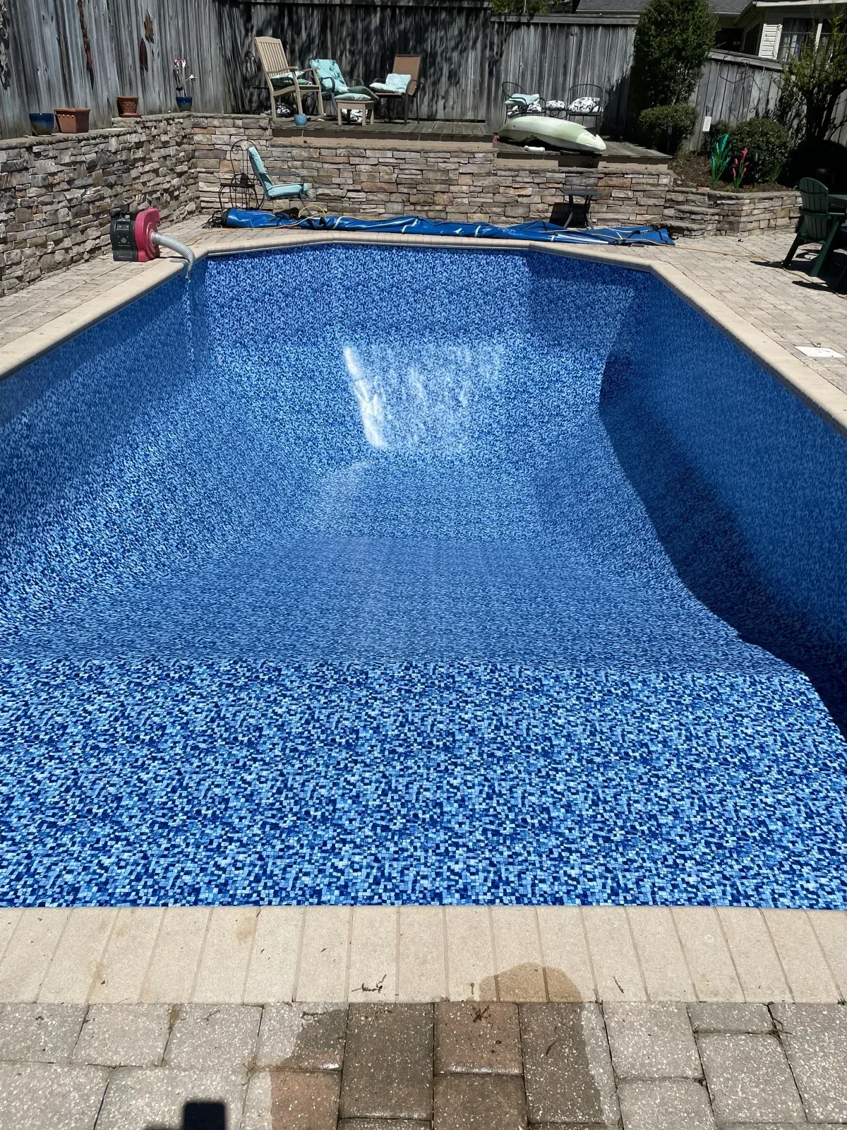 In-ground pool with blue mosaic tile interior finish and concrete coping