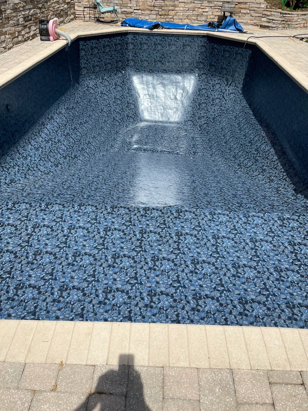 Newly resurfaced pool with blue aggregate finish and concrete coping