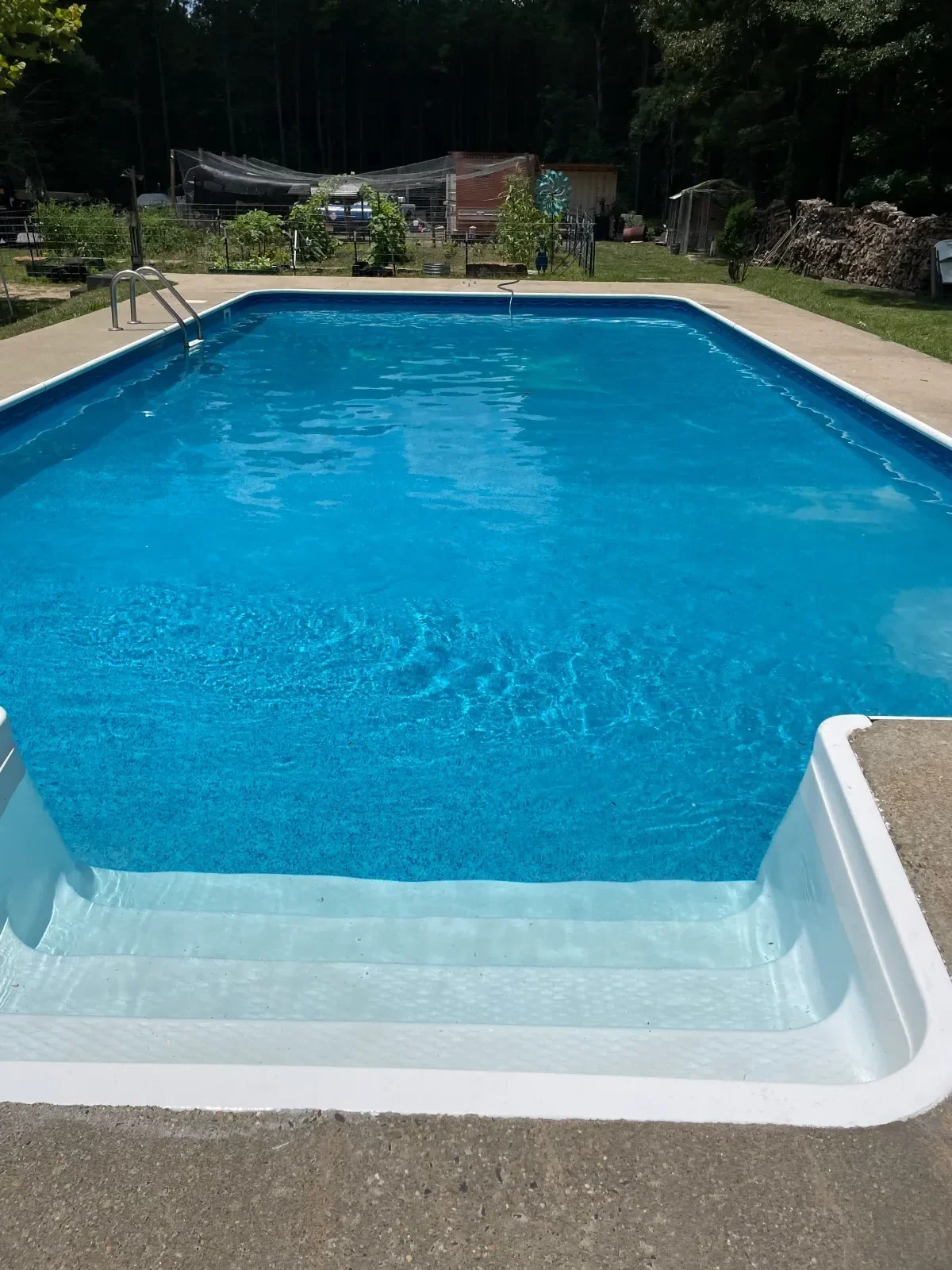 In-ground pool with blue interior finish, white coping, and clear water