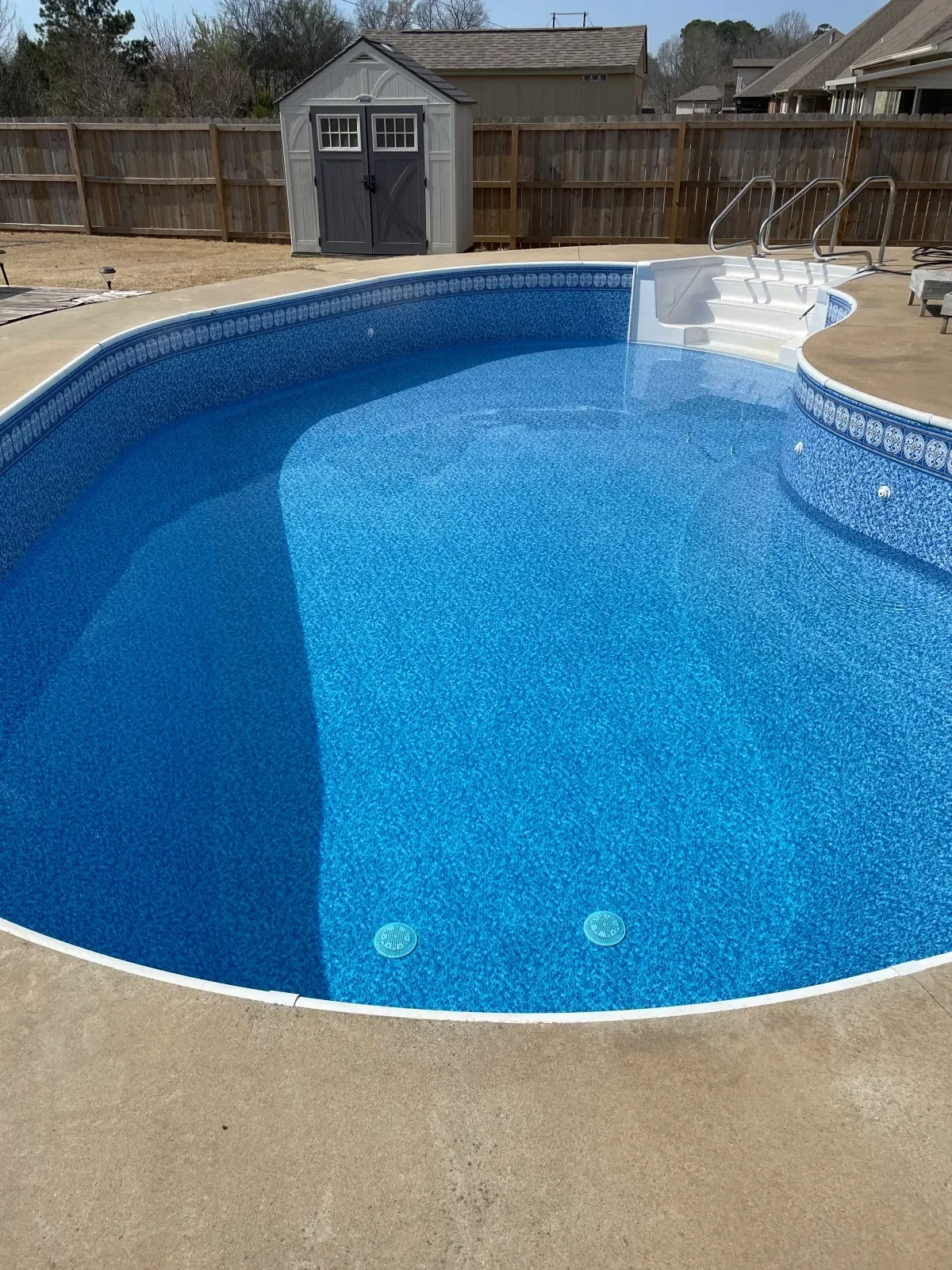 Aerial view of renovated in-ground pool with blue aggregate finish, white coping, and underwater lights